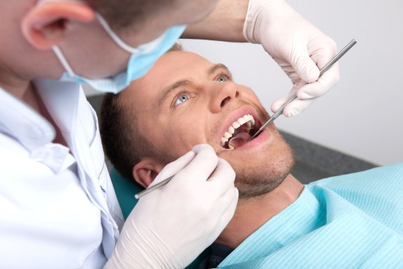 Patient at dentist office. Top view of man sitting at the chair in dental office and doctor examining teeth