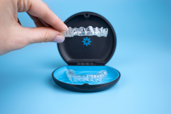 oman holding invisalign transparent retainers with a box on the table, flatlay top view. Selective focus.