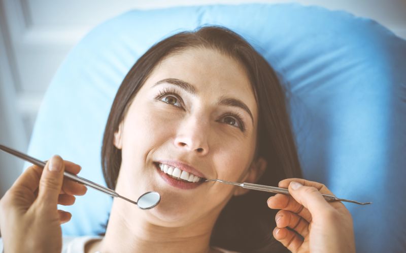 smiling-brunette-woman-being-examined-by-dentist at dental clinic hands of a doctor holding
