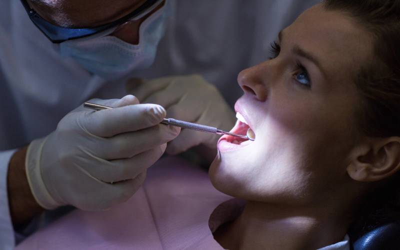 dentist examining a patient with tools